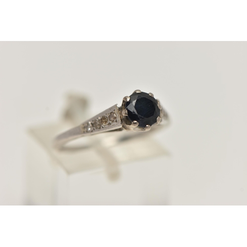 53 - A WHITE METAL GEM SET RING, a circular cut sapphire in a prong setting, leading on to tapered should... 