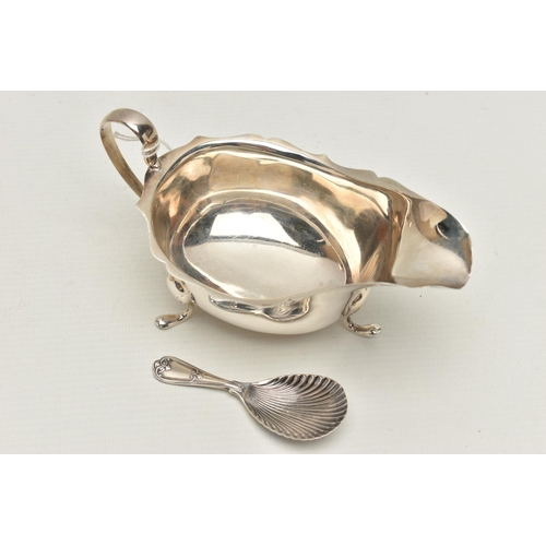 153 - A SILVER GRAVY BOAT AND A CADDY SPOON, polished form with wavy rim and scrolling handle, raised on t... 