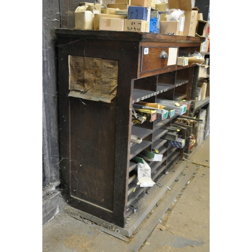 963 - AN EARLY 20th CENTURY OAK CABINET with slots for shelves and dividers below a single drawer (two doo... 