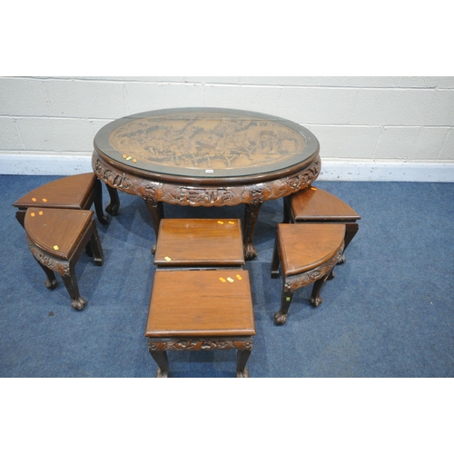 1206 - AN ORIENTAL CARVED OVAL COFFEE TABLE, with a sit on glass top, along with six smaller tables underne... 