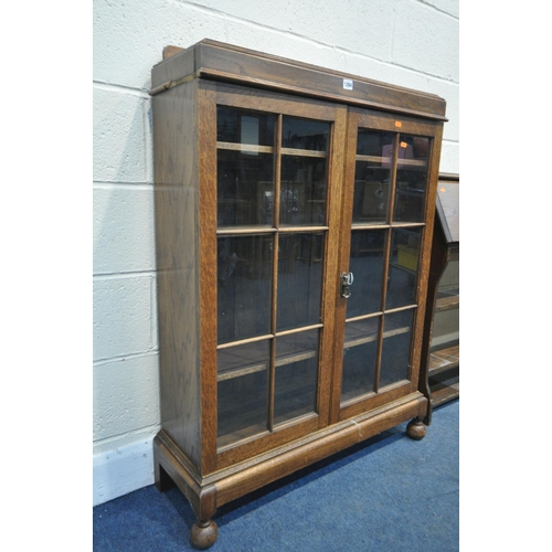 1264 - A 20TH CENTURY OAK GLAZED DOUBLE DOOR BOOKCASE, with a raised back and bun feet, width 85cm x depth ... 