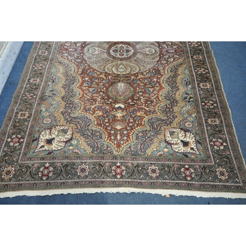 1274 - A KERMAN STYLE WOOLLEN RUG, with a central design within a red fields and multi strap border, 290cm ... 