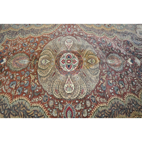 1274 - A KERMAN STYLE WOOLLEN RUG, with a central design within a red fields and multi strap border, 290cm ... 