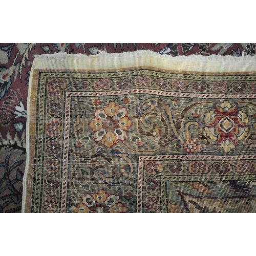 1274 - A KERMAN STYLE WOOLLEN RUG, with a central design within a red fields and multi strap border, 290cm ... 