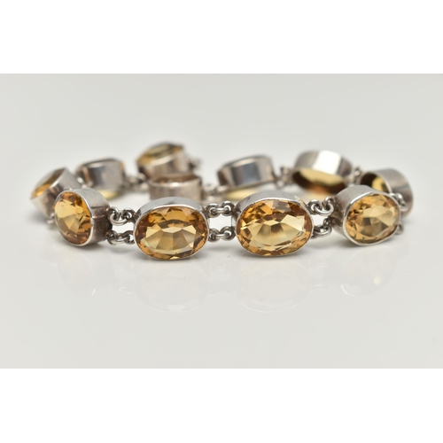 20 - A WHITE METAL CITRINE LINE BRACELET, designed as a series of slightly graduated, oval cut citrines, ... 