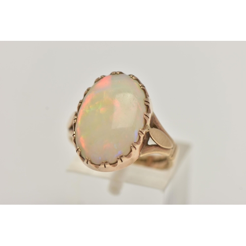 29 - A 9CT GOLD OPAL RING, large oval opal cabochon, showing flashes of all the colours in the spectrum, ... 