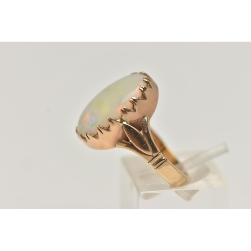 29 - A 9CT GOLD OPAL RING, large oval opal cabochon, showing flashes of all the colours in the spectrum, ... 
