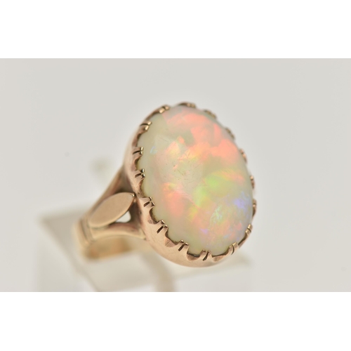 29 - A 9CT GOLD OPAL RING, large oval opal cabochon, showing flashes of all the colours in the spectrum, ... 