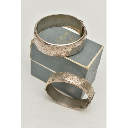 103 - TWO ELIZABETH II HINGED SILVER BANGLES, both with foliate engraved scrolls to one half, Birmingham 1... 