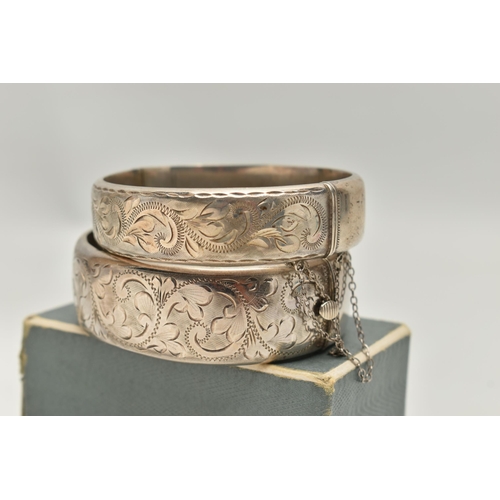 103 - TWO ELIZABETH II HINGED SILVER BANGLES, both with foliate engraved scrolls to one half, Birmingham 1... 