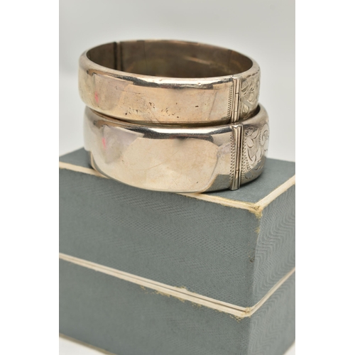 103 - TWO ELIZABETH II HINGED SILVER BANGLES, both with foliate engraved scrolls to one half, Birmingham 1... 