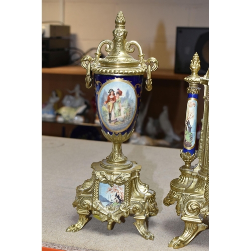 416 - A 20TH CENTURY BRASS AND PORCELAIN CLOCK GARNITURE, the porcelain panels transfer printed with coupl... 