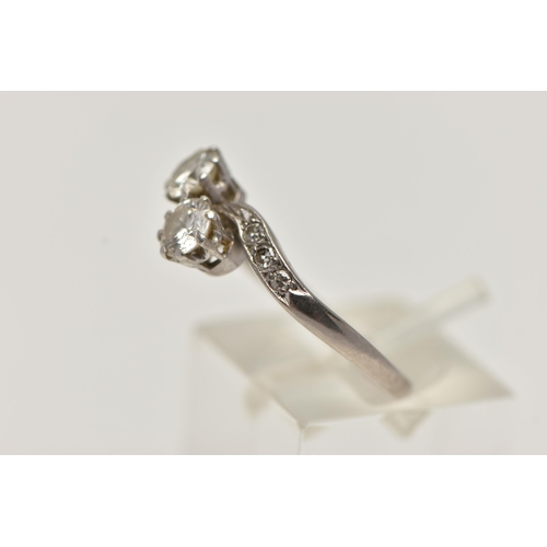 73 - A WHITE METAL DIAMOND CROSS OVER RING, set with two round brilliant cut diamonds, each claw set, app... 