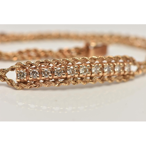 80 - A YELLOW METAL DIAMOND BRACELET, centring on a row of ten round brilliant cut diamonds, estimated to... 