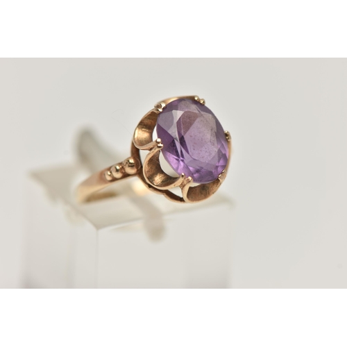 96 - A 9CT GOLD AMETHYST RING, an oval cut amethyst prong set in a yellow gold scalloped mount, hallmarke... 