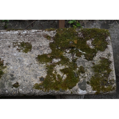 1023 - A WEATHERED COMPOSITE GARDEN BENCH, with a rectangular top, resting on twin pedestals depicting squi... 