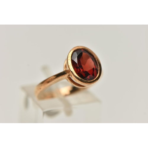 17 - A 9CT GOLD GARNET RING, oval cut garnet in a collet setting, mount measuring approximately length 11... 