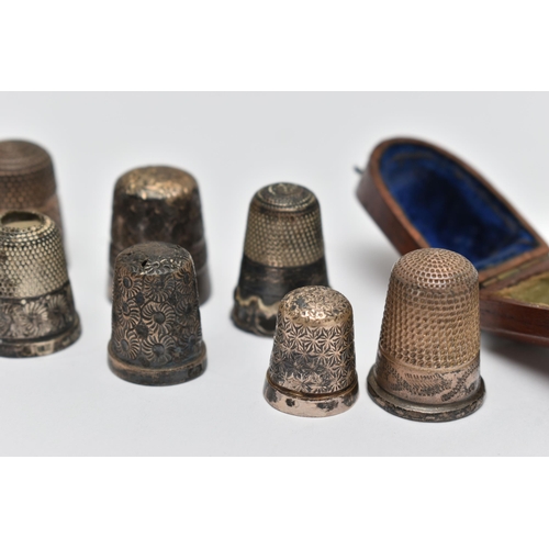 82 - A LATE VICTORIAN WOODEN CASED SILVER THIMBLE AND EIGHT OTHER SILVER / WHITE METAL THIMBLES,  the cas... 