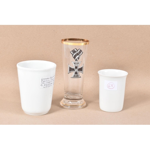 298 - TWO GERMAN WWII WHITE GLAZED CERAMIC BEAKERS AND A LATER DRINKING GLASS DECORATED WITH AN WWI IMPERI... 