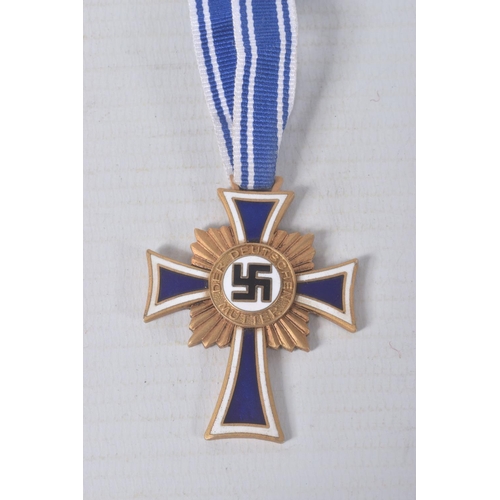 324 - A GERMAN GOLD MOTHERS CROSS, this comes on a length of ribbon and has the inscription on the back, C... 