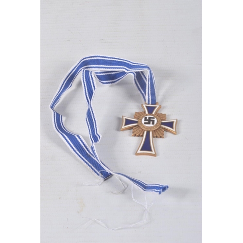 324 - A GERMAN GOLD MOTHERS CROSS, this comes on a length of ribbon and has the inscription on the back, C... 