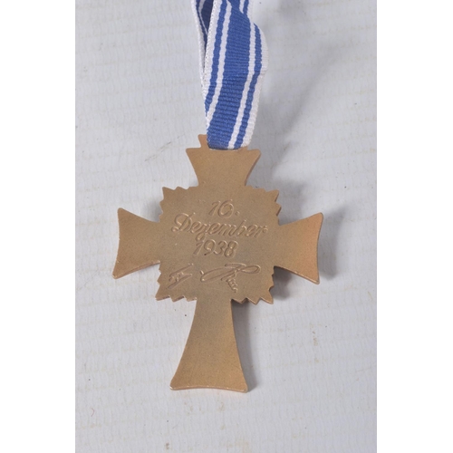 324 - A GERMAN GOLD MOTHERS CROSS, this comes on a length of ribbon and has the inscription on the back, C... 