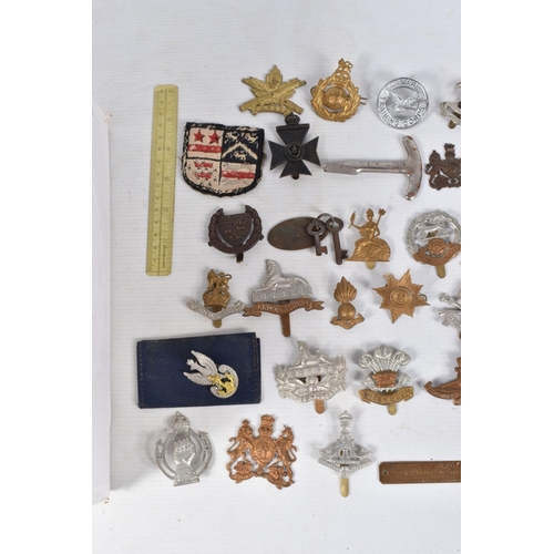 354 - A BOX CONTAINING OVER THIRTY FIVE CAP BADGES, and an assortment soft back magazines relating to WWII... 