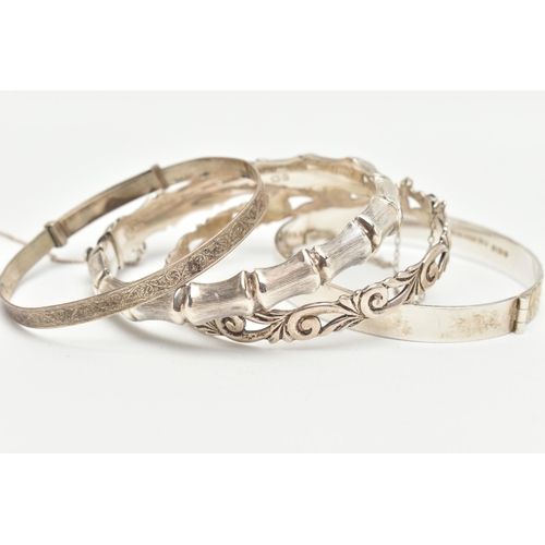 116 - THREE SILVER BANGLES, the first a bamboo style hinged bangle, the second an open work foliage hinged... 