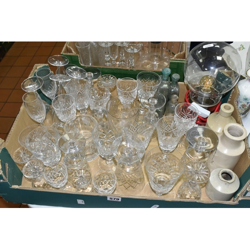 579 - TWO TRAYS OF GLASSWARE, to include four vintage medicine bottles, eleven champagne flutes, decanter,... 