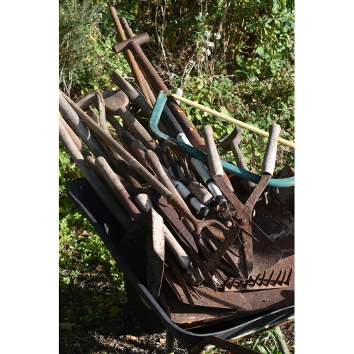 1014 - A WHEELBARROW CONTAINING VARIOUS GARDEN TOOLS, to include rakes, shovels, pitch forks, etc (conditio... 