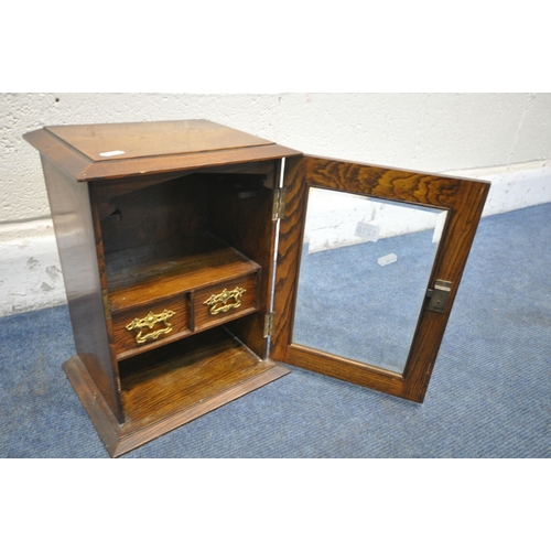 1216 - AN EARLY 20TH CENTURY OAK SMOKERS CABINET, with a glazed door enclosing two drawers, width 28cm x de... 