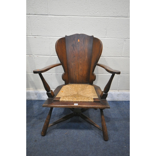 1254 - AN OAK GOTHIC OPEN ARMCHAIR, with a rush seat, along with a Heals of London style open armchair (con... 