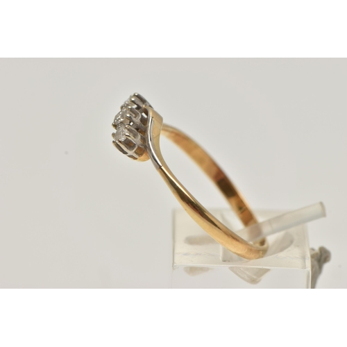 33 - A YELLOW METAL THREE STONE DIAMOND RING, of a cross over design, set with a central round brilliant ... 