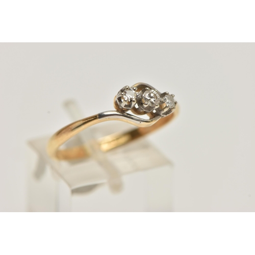 33 - A YELLOW METAL THREE STONE DIAMOND RING, of a cross over design, set with a central round brilliant ... 