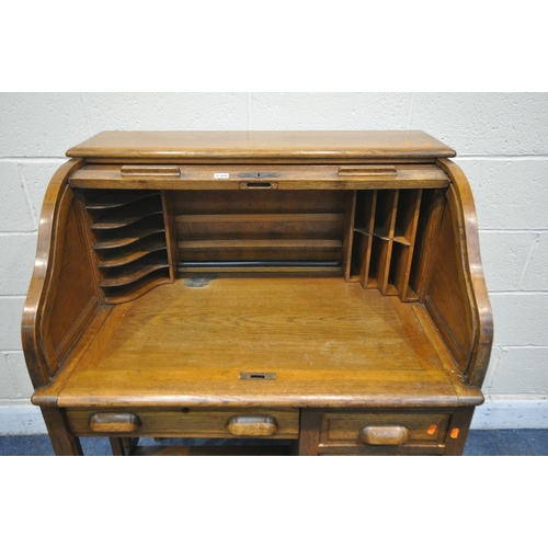 1198 - AN EARLY TO MID 20TH CENTURY OAK ROLL TOP DESK, enclosing an arrangement of pigeon holes, over five ... 