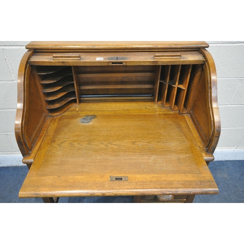 1198 - AN EARLY TO MID 20TH CENTURY OAK ROLL TOP DESK, enclosing an arrangement of pigeon holes, over five ... 