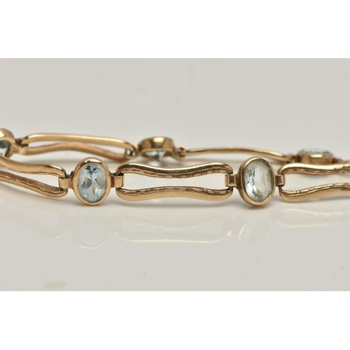 7 - AN AQUAMARINE BRACELET, five oval cut aquamarines bezel set in yellow metal interspaced between elon... 