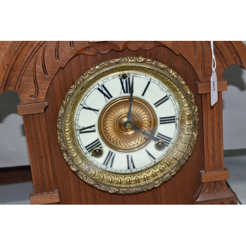 486 - A LATE 19TH CENTURY WALNUT CASED AMERICAN ANSONIA MANTEL CLOCK, the carved pediment above enamel dia... 