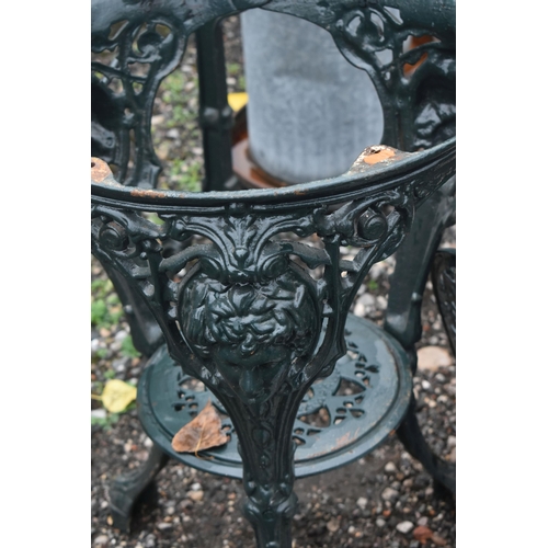 1016 - A GREEN PAINTED CAST IRON TABLE BASE, with foliate detail surrounding a face to each leg, diameter 4... 