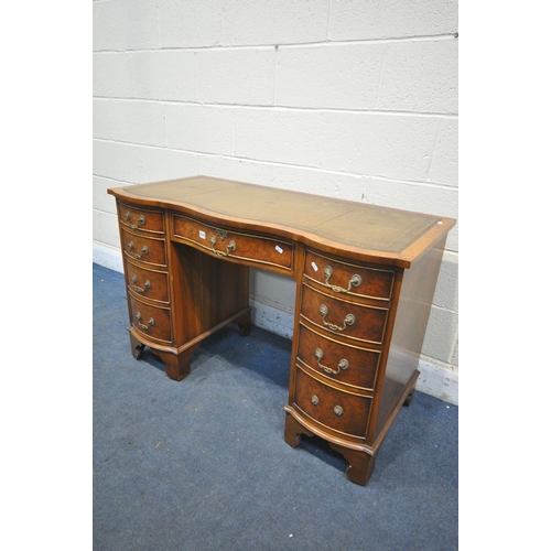 1216 - A BEVAN FUNNELL REPRODUCTION WALNUT SERPENTINE DESK, with a green leather writing surface, nine draw... 