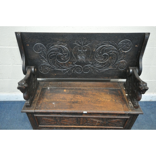 1304 - AN EARLY 20TH CENTURY CARVED OAK MONKS BENCH, with a pivoting top, and storage compartment, width 12... 