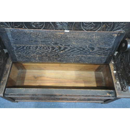 1304 - AN EARLY 20TH CENTURY CARVED OAK MONKS BENCH, with a pivoting top, and storage compartment, width 12... 