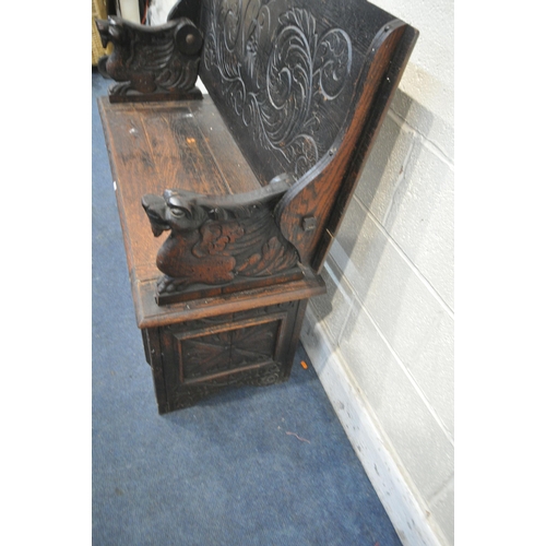 1304 - AN EARLY 20TH CENTURY CARVED OAK MONKS BENCH, with a pivoting top, and storage compartment, width 12... 