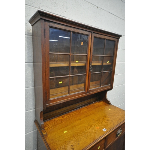 1333 - AN EARLY 20TH CENTURY OAK BOOKCASE, with double glazed doors, over a base with two drawers, and doub... 