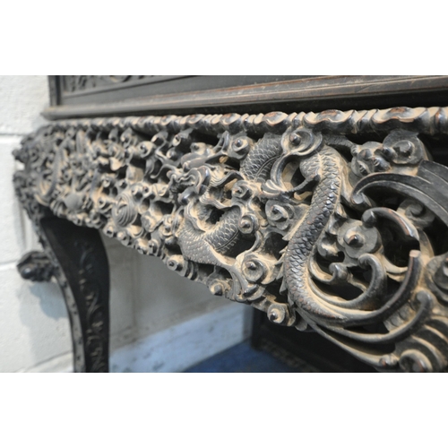 1353 - A 19TH CENTURY EBONISED ROSEWOOD CHINESE BOOKCASE ABOVE DESK, heavily carved throughout with dragons... 