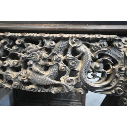 1353 - A 19TH CENTURY EBONISED ROSEWOOD CHINESE BOOKCASE ABOVE DESK, heavily carved throughout with dragons... 