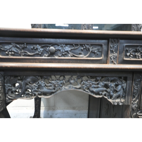 1353 - A 19TH CENTURY EBONISED ROSEWOOD CHINESE BOOKCASE ABOVE DESK, heavily carved throughout with dragons... 