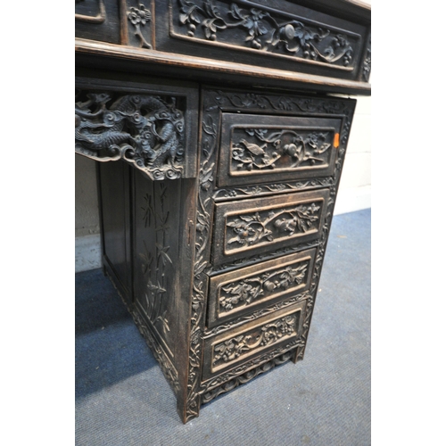 1353 - A 19TH CENTURY EBONISED ROSEWOOD CHINESE BOOKCASE ABOVE DESK, heavily carved throughout with dragons... 