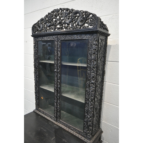 1353 - A 19TH CENTURY EBONISED ROSEWOOD CHINESE BOOKCASE ABOVE DESK, heavily carved throughout with dragons... 