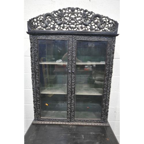 1353 - A 19TH CENTURY EBONISED ROSEWOOD CHINESE BOOKCASE ABOVE DESK, heavily carved throughout with dragons... 